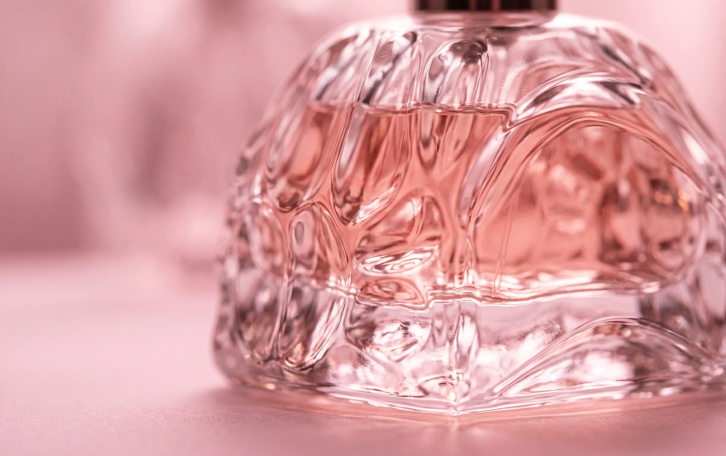 détail macro de la texture du verre d'un parfum moderne dans des tons doux